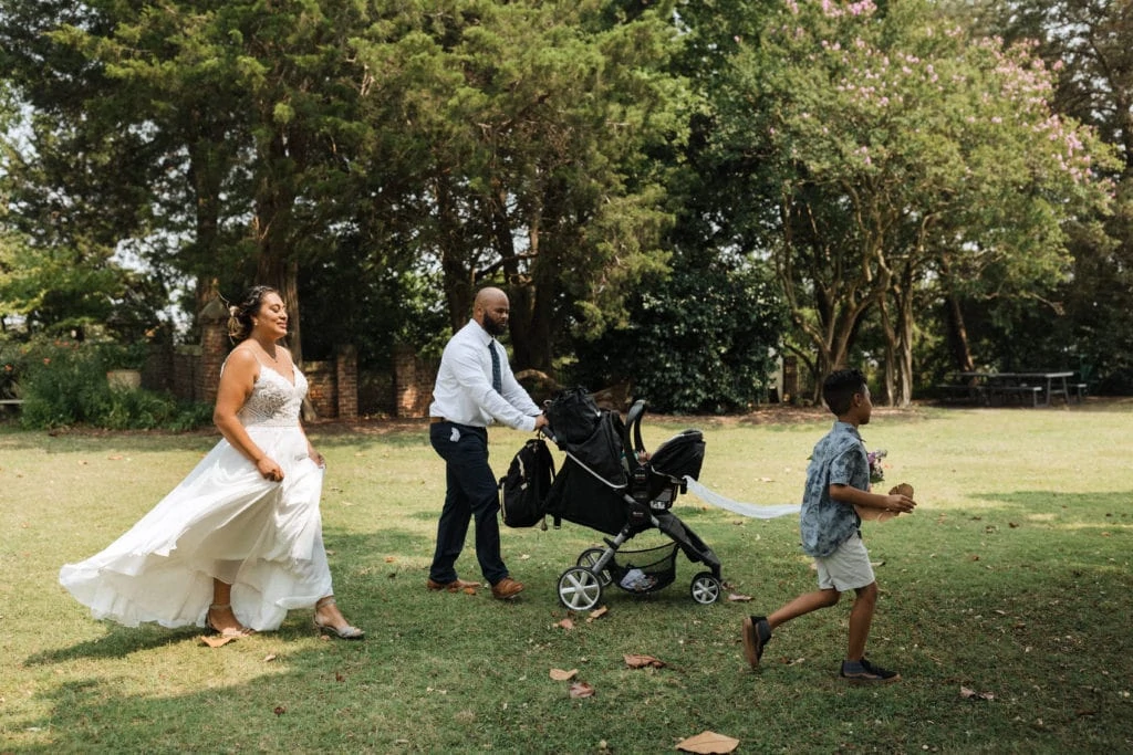 a bride, groom, and their children walk across the gardens to their elopement spot