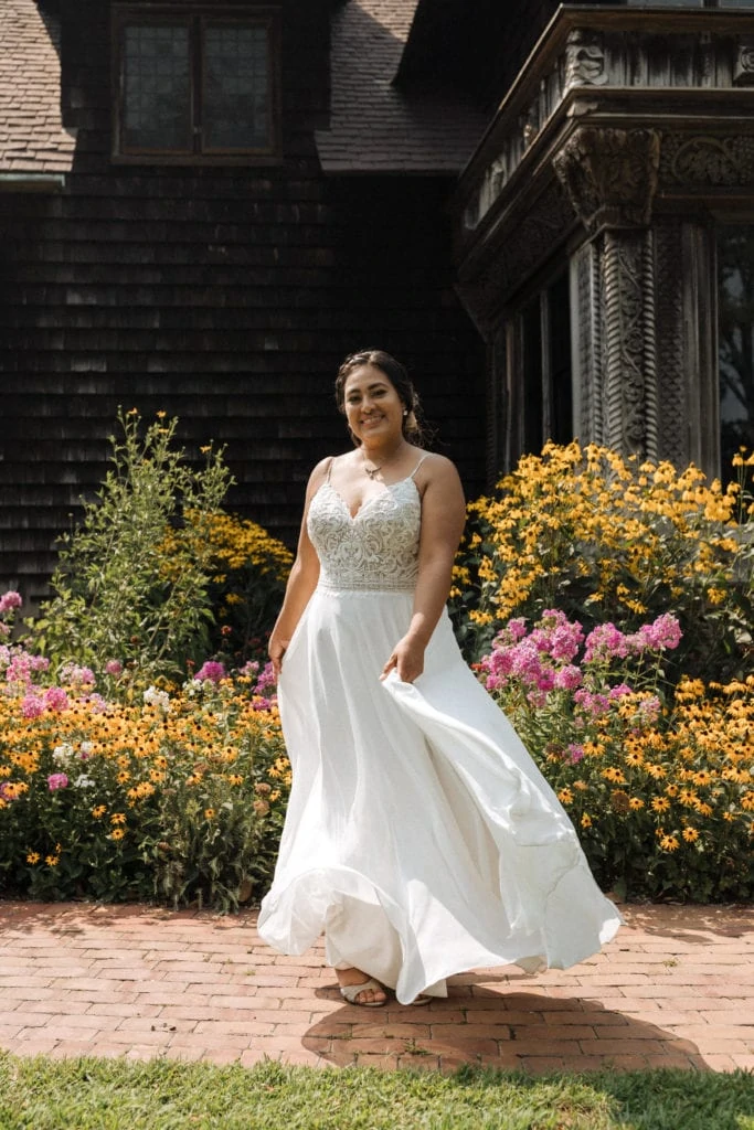 bride twirling her dress smiling in front of flowers