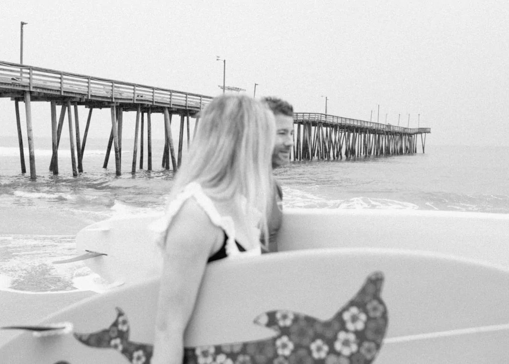 black and white photo of the virginia beach fishing pier with a couple in the foreground out of focus