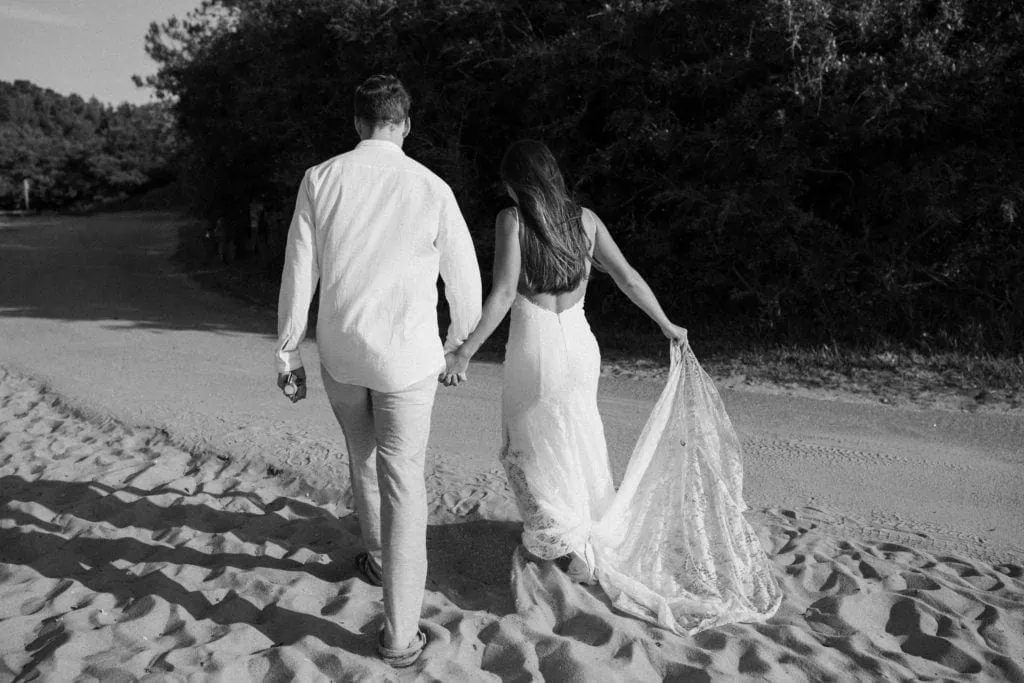 a bride and groom walk hand in hand on the beach at a virginia state park after saying their vows