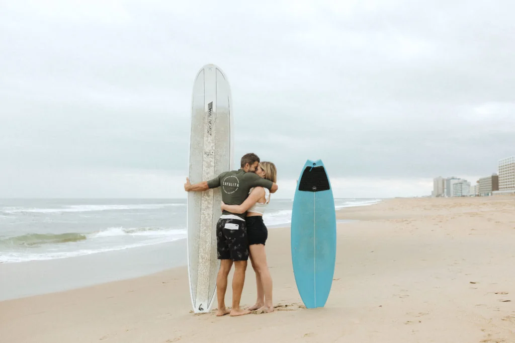 a couple kiss their surfboards are in the sand sticking up