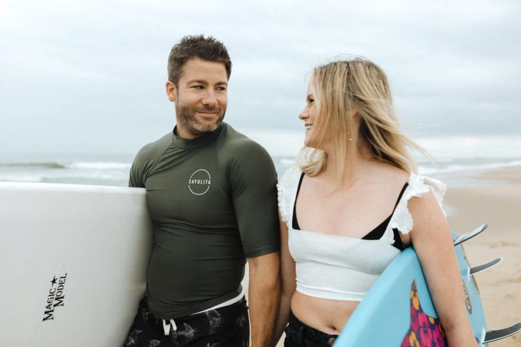 a couple looking at each other smiling while in beach clothes