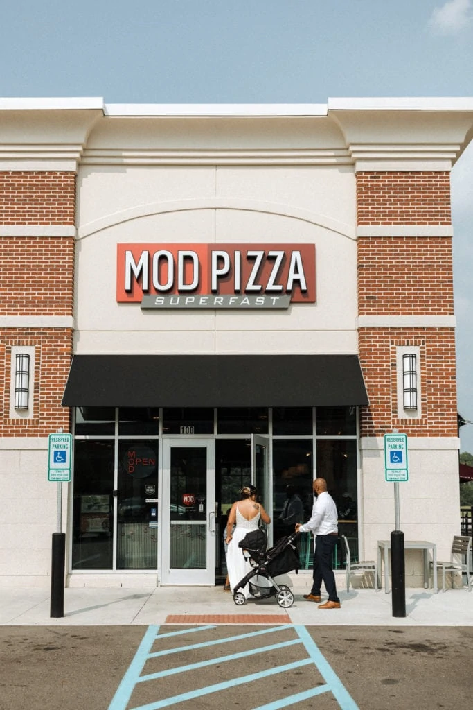 bride, groom and their family go into mod pizza