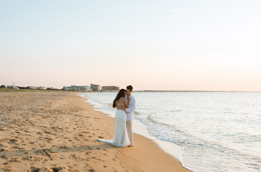 a couple hugging on the beach at sunset after their elopement