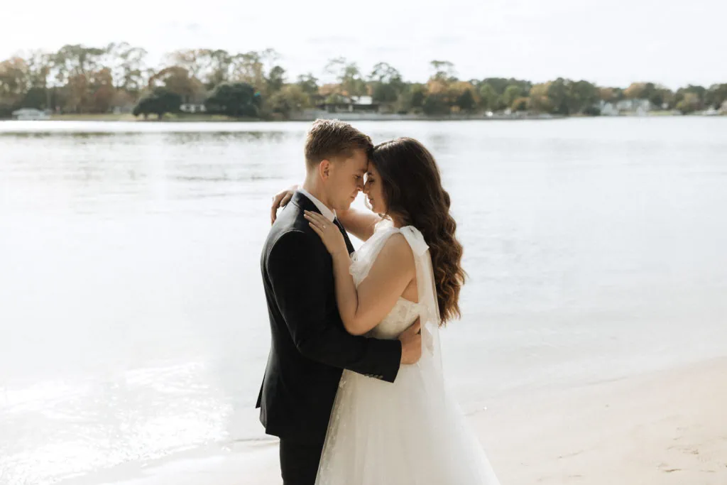 a couple embrace on the beach in their wedding attire