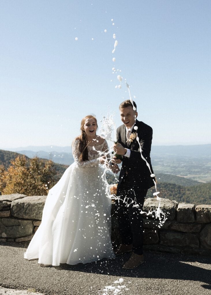 bride and groom pop champagne in the mountains laughing 
