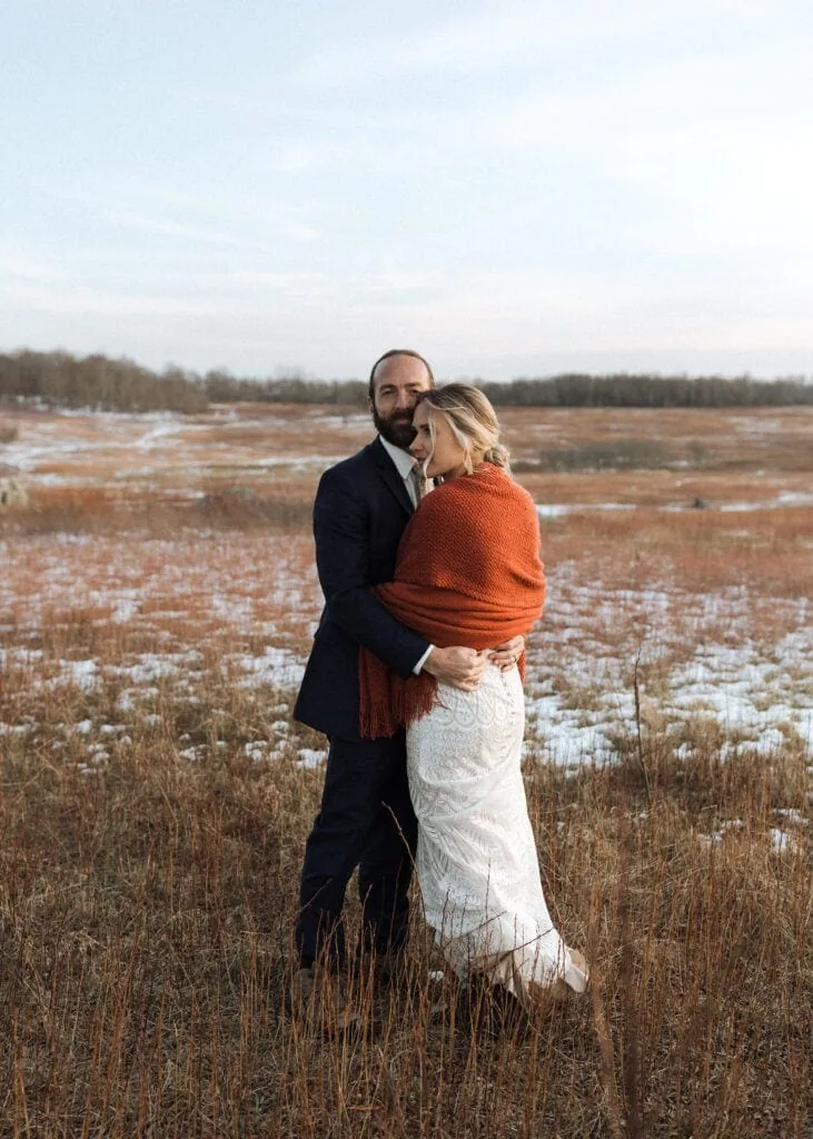 a bride and groom hug in a big field