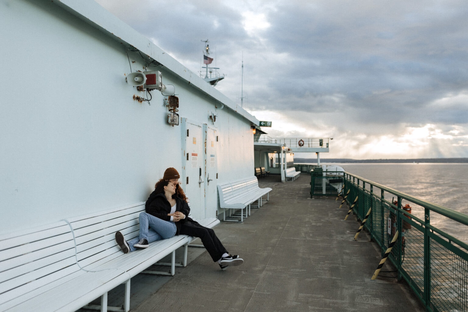 a couple relax on the seattle ferry at sunset for their engagement photos